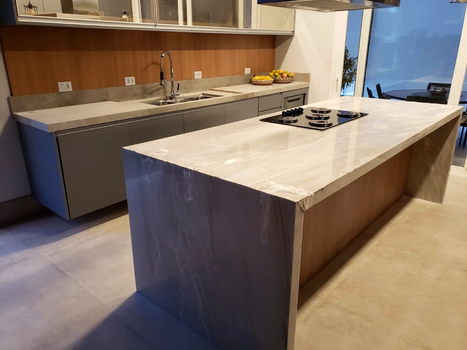 Ilha de cozinha em pedra com laterais em cascata e cooktop embutido