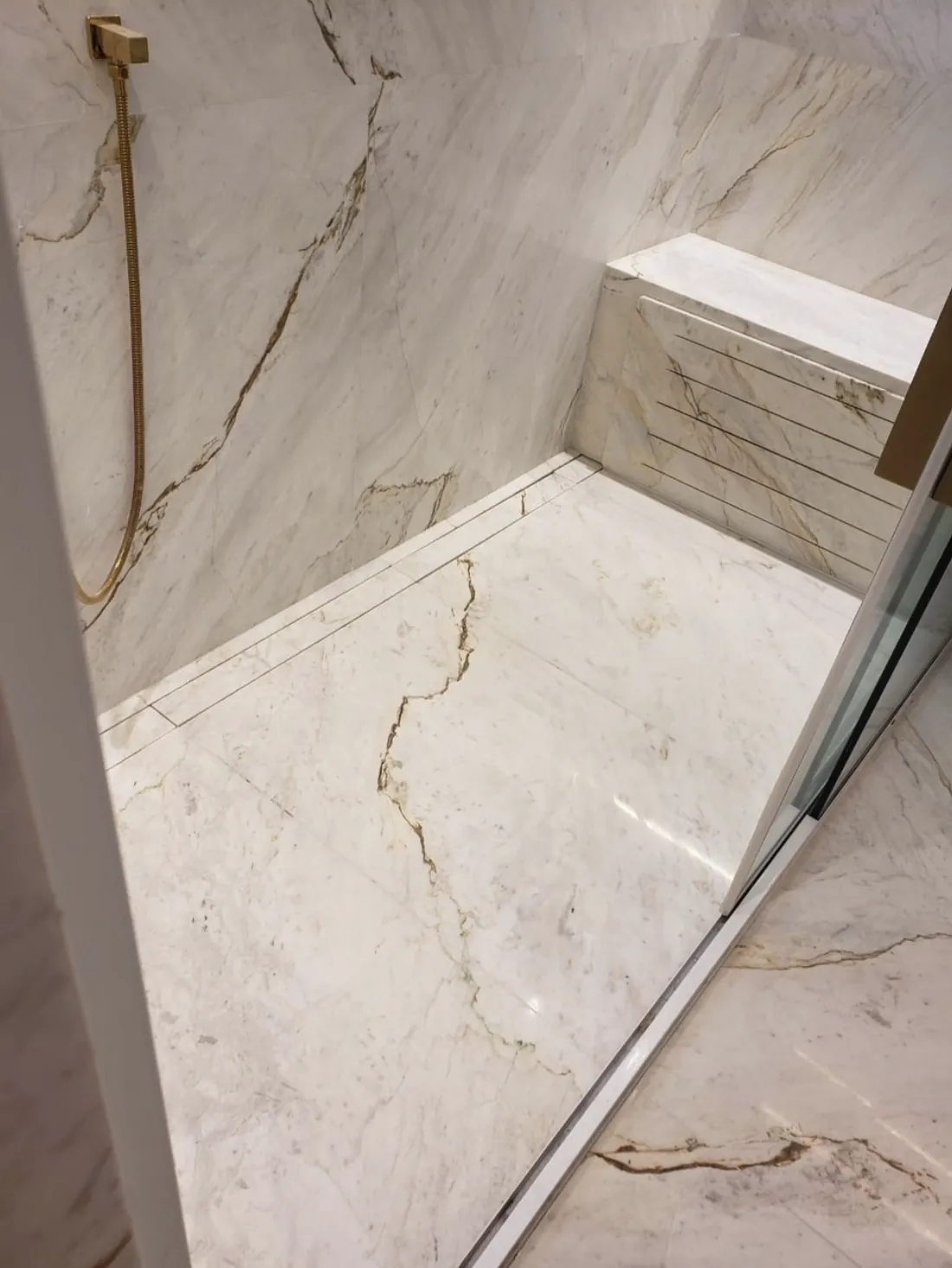 Banheiro paginado em pedra natural: Banco e piso do box com ralo linear