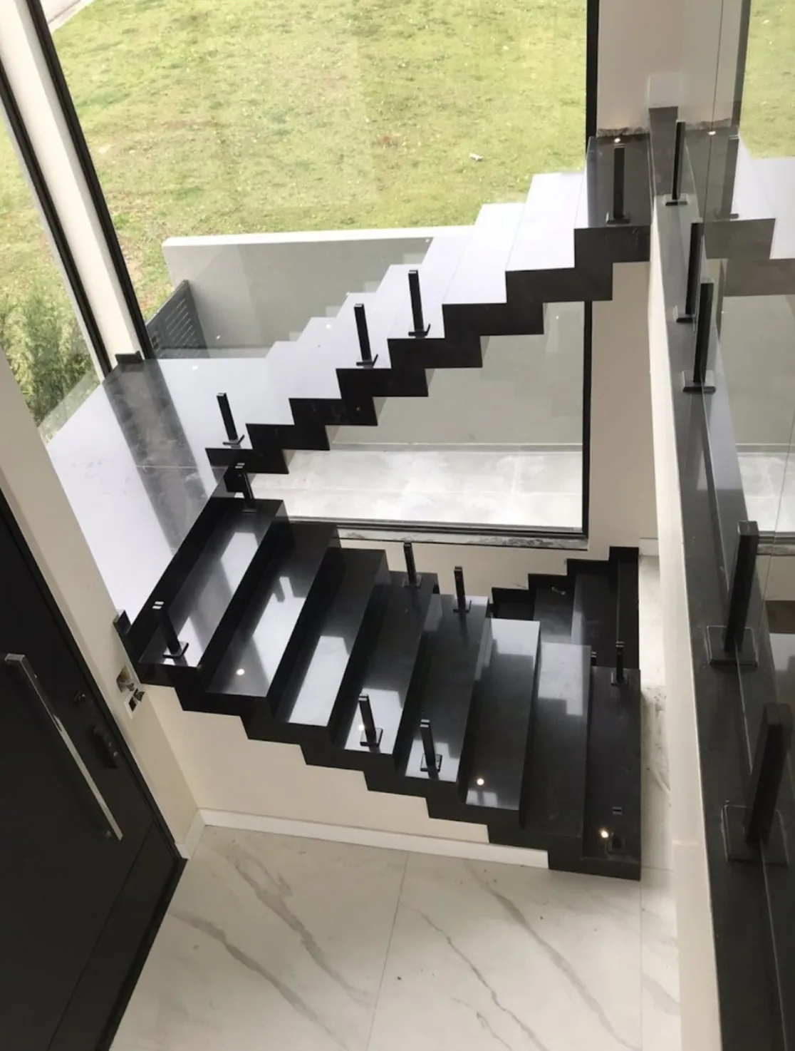 Revestimento de escada em pedra natural: Escada em granito preto com guarda-corpo de vidro