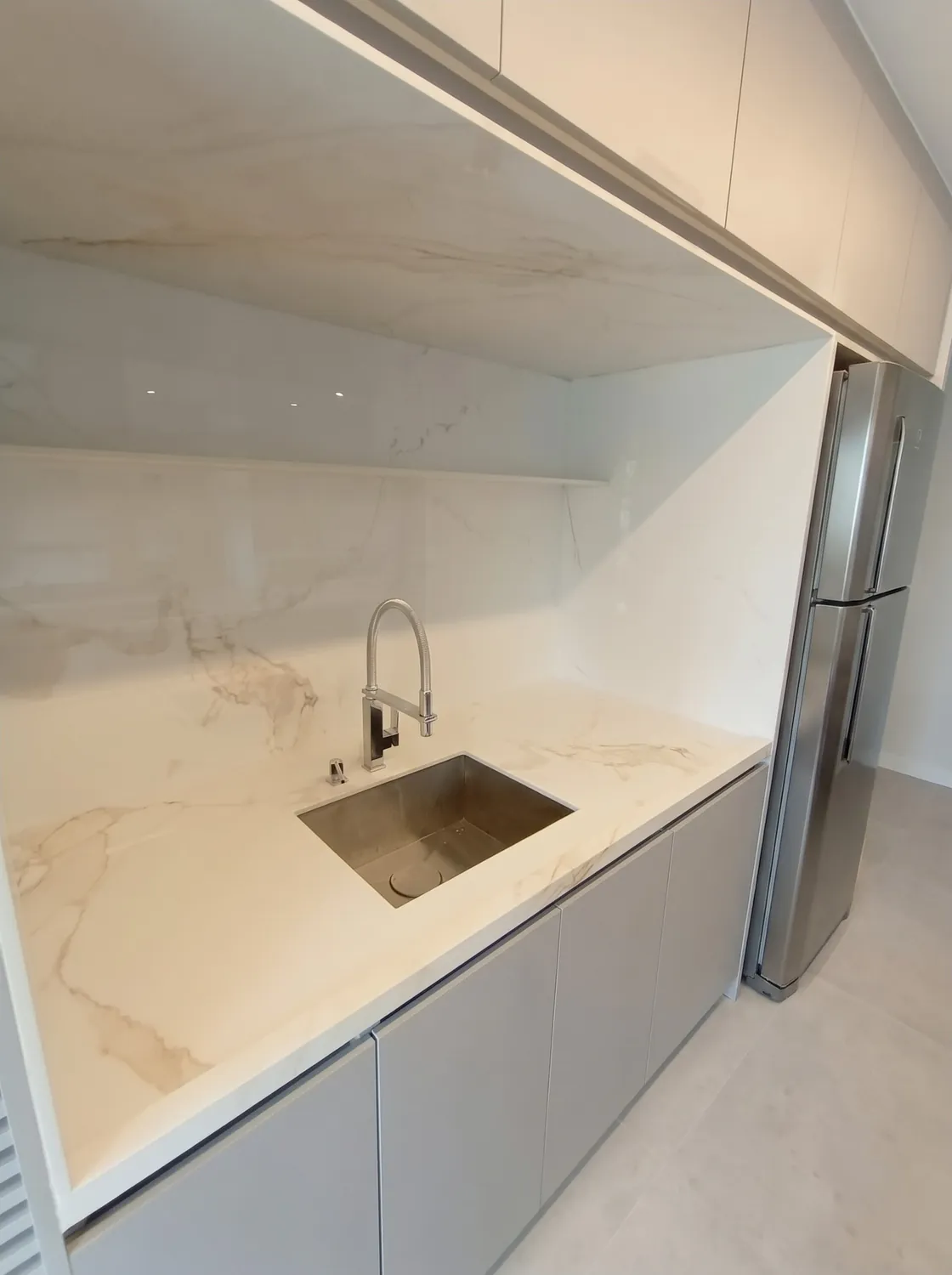 Cozinha com ilha em cascata em pedra natural: Bancada da pia com cuba embutida e frontão