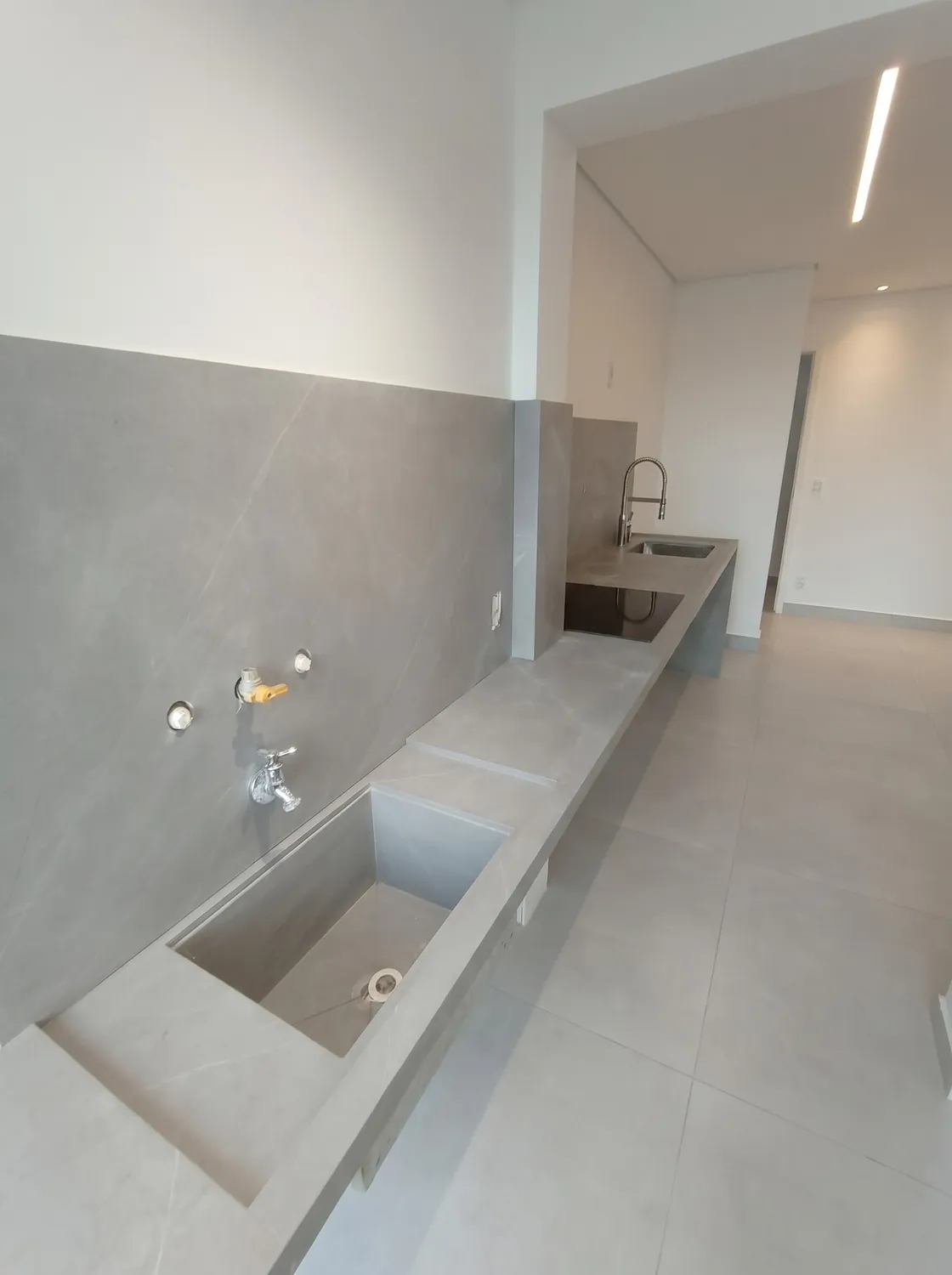 Apartamento em lâmina cinza em pedra natural: Bancada com cuba esculpida na própria lâmina
