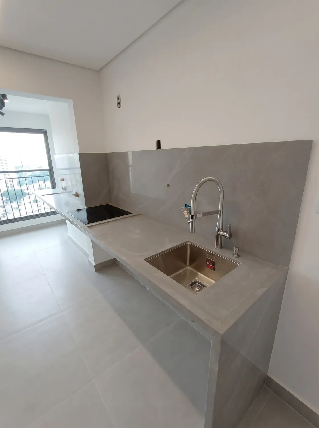 Apartamento em lâmina cinza em pedra natural: Cozinha com bancada, cooktop e cuba de inox